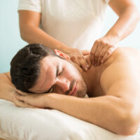 Deep tissue massage at a spa Very relaxed young Latin man getting a deep tissue massage on his back in a wellness and spa clinic